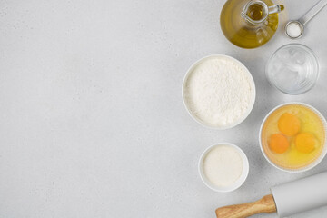 Ingredients for baking on a white plate with copy space. Ingredients for baking: eggs, olive oil, water, flour, sugar on a white background top view