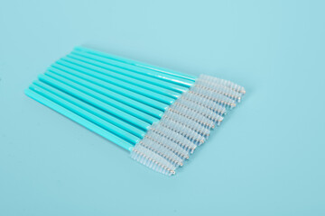 Makeup brushes, eyelash combs and eyebrows on blue background with copy space