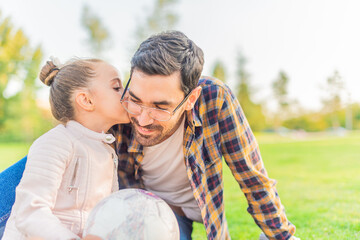 cute little girl kissing her single father in a park