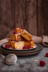 Breakfast: cottage cheese cubes syrniki  with raspberries, almond petals and powdered sugar on a gray concrete background. 

