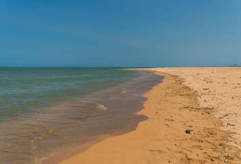 praia deserta com areias escuras e céu azul