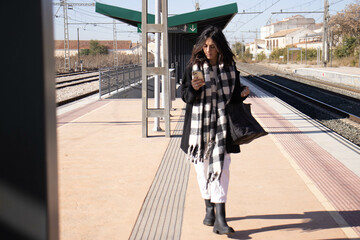 Obraz premium young brunette woman next to railroad arden with luggage, waiting for passenger train.