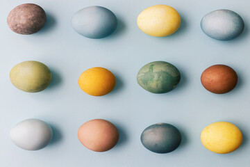Easter composition. Stylish colorful eggs flat lay on blue background. Modern natural dyed colorful easter eggs layout. Greeting card template, easter background