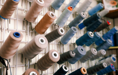 Beautiful multicolored sewing threads For the textile industry. A row of multicolored spools of sewing thread.