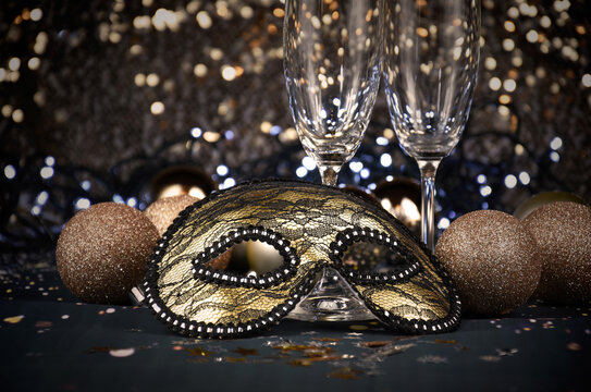 New Year's Eve celebration party with champagne glasses and golden carnival mask stock images. Masquerade half face mask and blurred lights stock photo. New Year party still life images