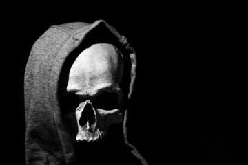Human skull in hood close up on black background - obrazy, fototapety, plakaty