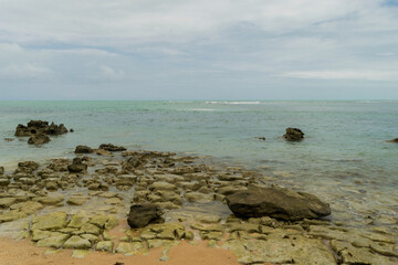 Linda vista de praia com muitas pedras e um céu azul