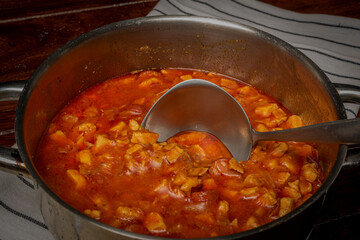 Chicken goulash in metal cooking pot on wooden table