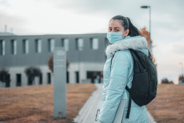 Obraz premium Estudiante de la facultad con mascarilla paseando por el campus de la universidad junto con su mochila para entrar al aula 
