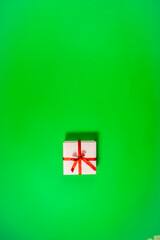 One holiday pink gift box tied with red ribbon on green background.