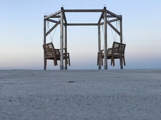 Scenic view of outdoor hexagonal prism with four wood swing rocking chairs on the paved pier of...
