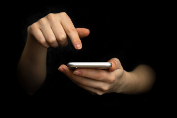 Businesswoman uses and touch the mobile phone, front view. Black background, hands and smartphone close-up. High tech, technology and communication concept photo