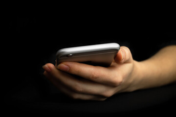 Person uses mobile phone, front view. Black background, hand and smartphone close-up. High tech, technology and communication concept photo