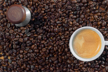 A cup of espresso and coffee temp with a coffee bean background