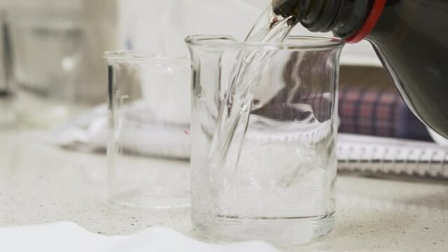 Pouring a solvent into the chemical beaker for pharmaceutical or chemical analysis. 