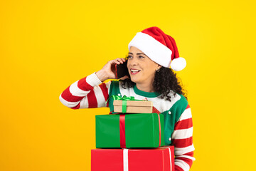 Portrait of adult latin woman calling by mobile phone in a christmas concept on yellow background in Mexico Latin America