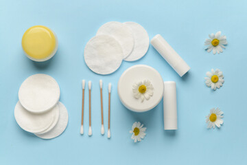 Care cosmetics, cotton buds, cotton pads and Chamomile flowers on color background