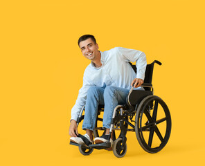 Young man in wheelchair on color background