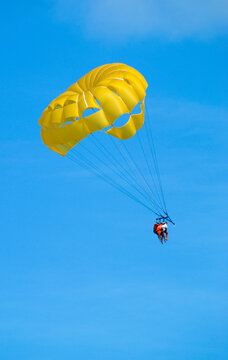 Yellow parasailing in blue sky with 3 people towed in Punta Cana
