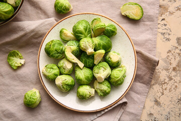 Plate with fresh raw Brussels cabbage on color background