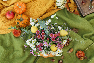 Beautiful bouquet of autumn flowers in pumpkin on warm plaid
