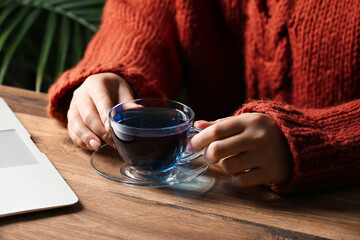 Woman drinking butterfly pea flower tea at table