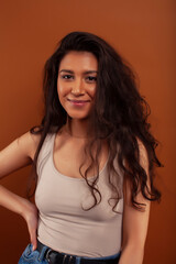 Naklejka premium cute happy young indian woman posing cheerful on brown background in studio close up smiling, fashion beauty