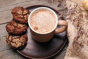 Cup of tasty pumpkin coffee and cookies on wooden background