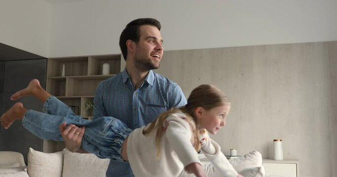 Plane is flying. Happy young single dad entertaining overjoyed preteen daughter hold child on hands swing in air imitating flight. Excited little girl enjoy playing together with father elder brother