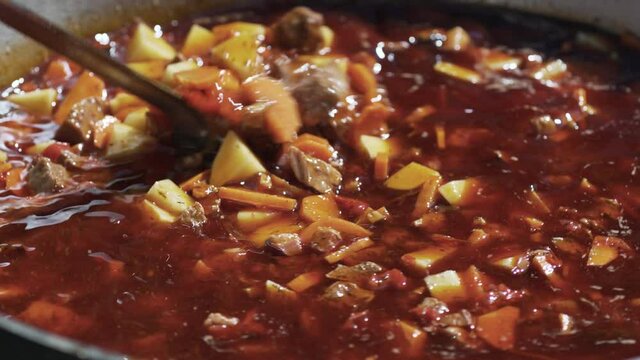 Hungarian traditional bograch. Making stew on open fire. german comfort food. Traditional Hungarian Goulash in cauldron. Transcarpathian dish. Soup with meat and paprika.