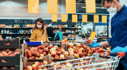 shoppers in protective masks standing in a supermarket at a safe distance