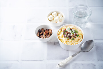 Corn porridge with fried bacon, parsley and Feta cheese in a bowl