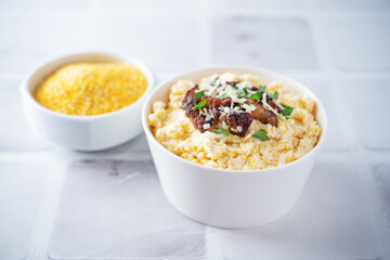 Corn porridge with fried bacon, parsley and Feta cheese in a bowl