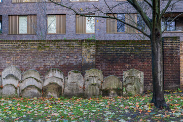 Ancient overgrown tombstones and graves in churchyard garden on autumn morning in background partly visible modern apartment block.