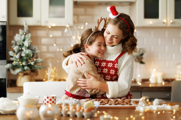 Loving mother and girl daughter hugging embracing while xmas cookies in kitchen on Christmas