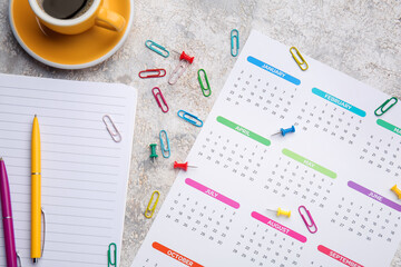 Paper calendar for year 2022, stationery supplies and cup of coffee on grunge background, closeup