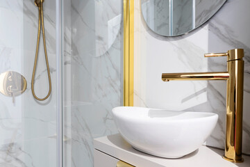 Ceramic bathroom sink with golden tap in modern elegant interior bathroom with marble on the wall. 