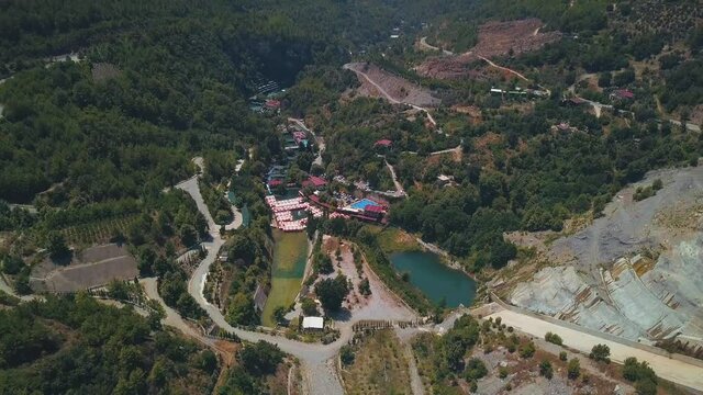 Summer bird's-eye view. Clip. A resort place located in the green mountains with a small clean lake and houses around.