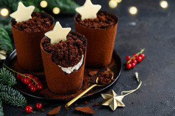 Obraz na płótnie Canvas Christmas dessert chocolate plant pots filled with cocoa biscuit crumbs and cream cheese, decorated with white chocolate stars. Festive creative dish. Selective focus
