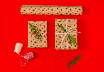 craft set for gift wrapping and two present boxes with thuja sprigs on red background