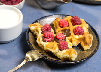 Croffles decorated with chocolate sauce and raspberries, and a cup of milk.A popular Asian dessert. Close-up, culinary trend.
