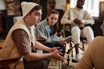 Guy talking to his teacher during a meeting in the classroom with other students