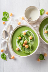 Green spinach soup with peas puff, leaves and cream.