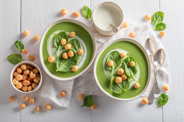 Creamy spinach soup with peas puff, leaves and cream.