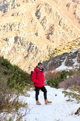 Obraz premium Hiker in a red jacket on a snowy mountain trail