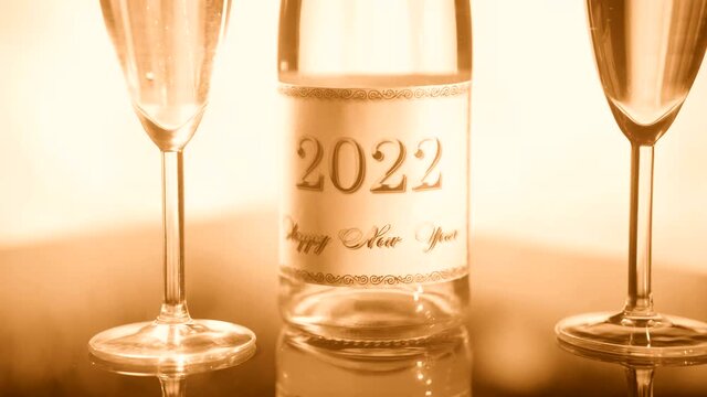 New Years Eve 2022. Image of a bottle of champagne and two glasses of champagne against the background of fireworks.  