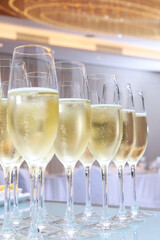 Gala dinner or event. Glasses with champagne on the table. Holidays concept. Party in a large bright hall. Secular reception. Buffet at a secular party.Lots of wine glasses. Vertical photo.