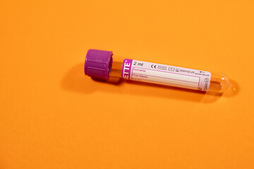 vacuum EDTA blood collection tube with purple cap on orange background, general blood analysis