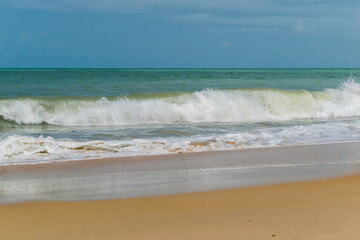 linda praia com areias escuras, ondas e céu azul