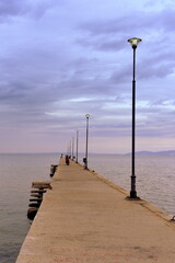 Weit ins Meer reichender Bootssteg vor dramatischem Himmel